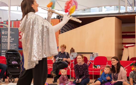 Woman plays flute with feathers on it to children