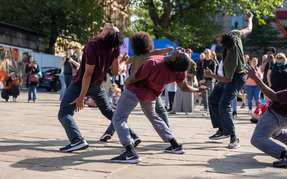 A performance group mid dance as a crowd watches