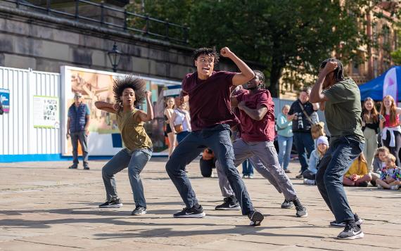 A performance group energetically dancing in front of a crowd