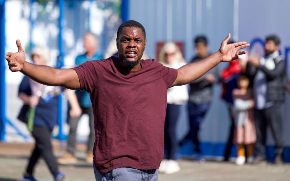 A man in the middle of a dance performance looking at the camera with arms open