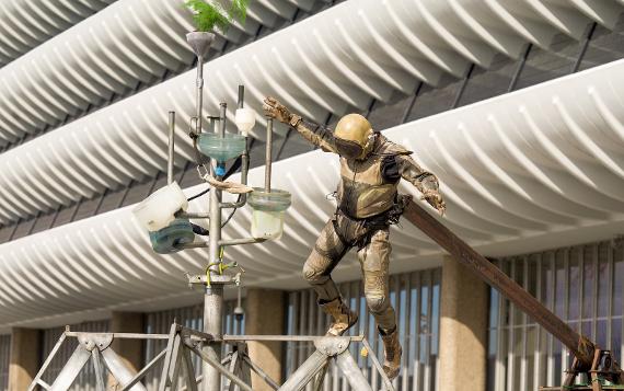 An astronaut lands on a metal frame holding plants and water