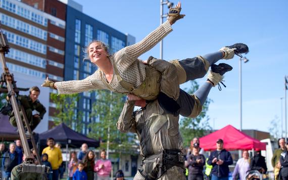 An astronaut holds up the woman as she pretends to fly