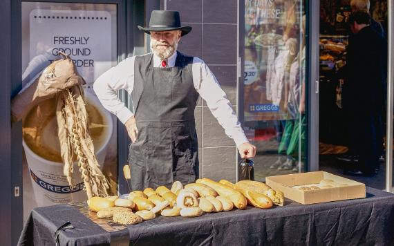 A man in a hat displays his loaves of bread for customers