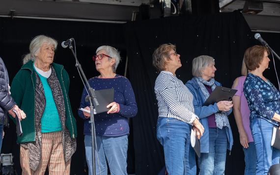 Five ladies from the Preston People's Choir singing on a stage