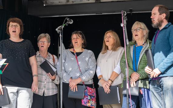 Preston People's Choir five ladies and a man singing in front of microphones