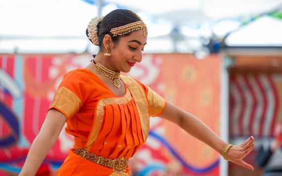 A Swati Dance Company dancer in a bright orange sari and golden jewellery