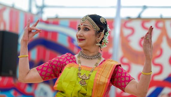 A woman from the Swati Dance Company poses while dancing in a red and green sari