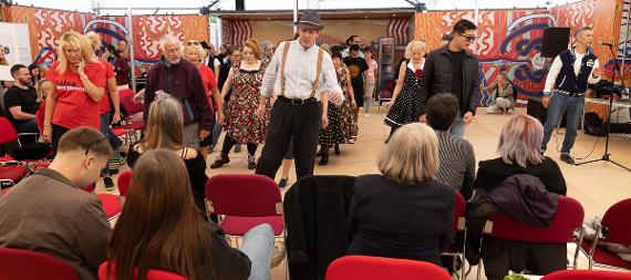 A group of people swing dancing on a dance floor in front of a seated audience