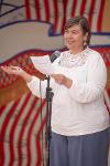 Esther Ferry-Kennington standing holding a piece of white paper making a speech into a microphone