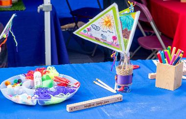 A table with a blue table cloth with pens, flags and arts and craft materials.