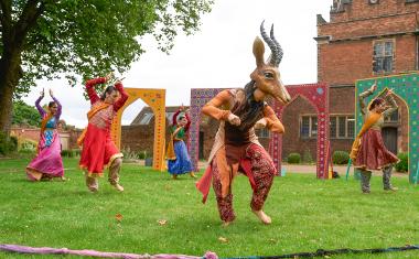 A person with a goat mask and a group of performers for Mughal Miniatures dancing