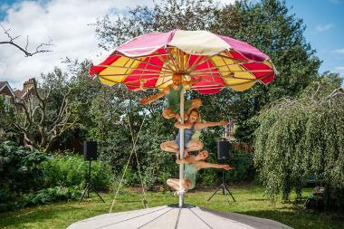 Three people under a large red and yellow parasol hanging to the pole posing for a photo