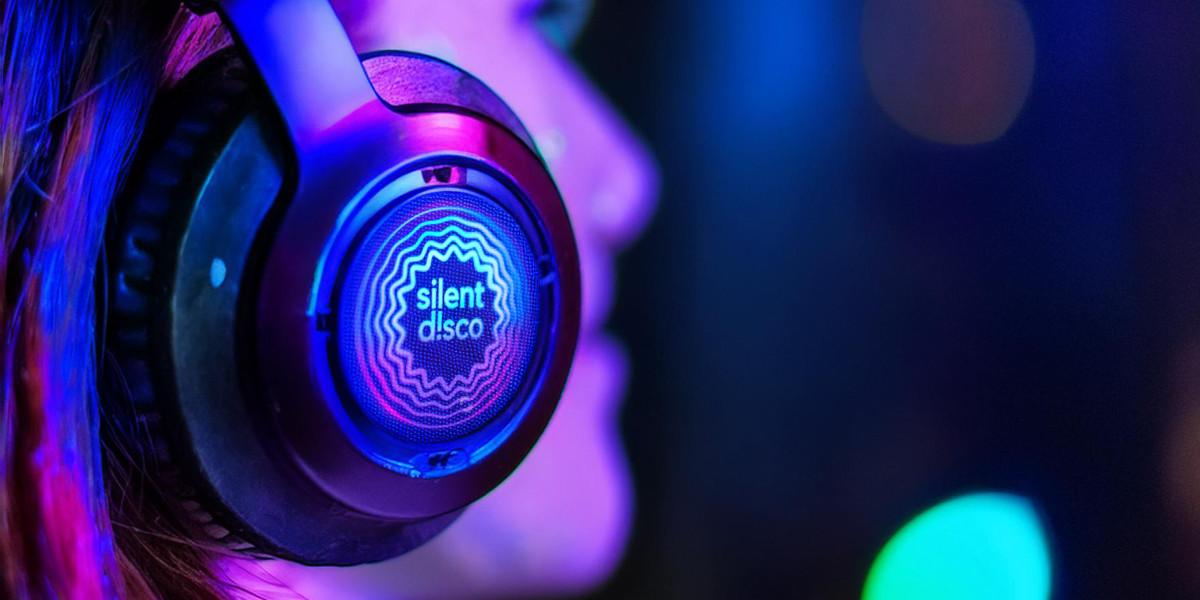 A person wearing headphones that say silent disco on them