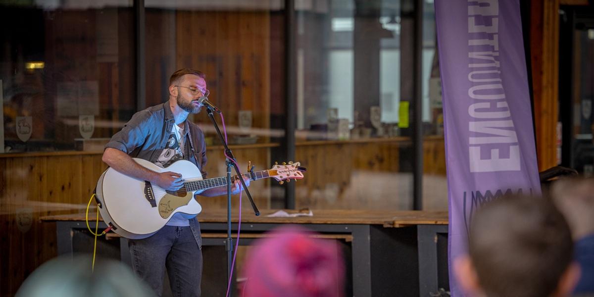 A man playing the guitar at Encounter Festival at Preston Market